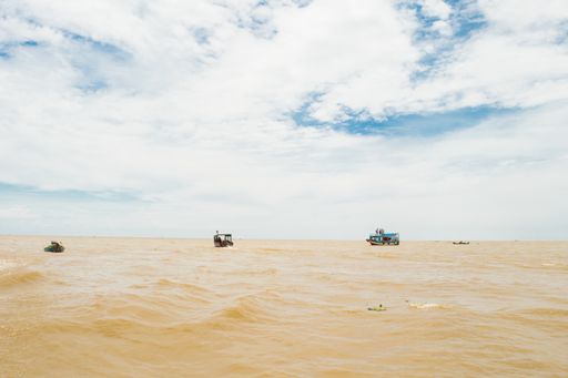 Colorful boat travelling on the brown muddy water of Tonle Sap Lake and river, near the fishing village of Kampong Phluk, Siem Reap, Cambodia, Asia.