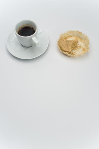 black hot ristretto coffe in a white stoneware cup with plate with nibbled pie on a white surface with text space