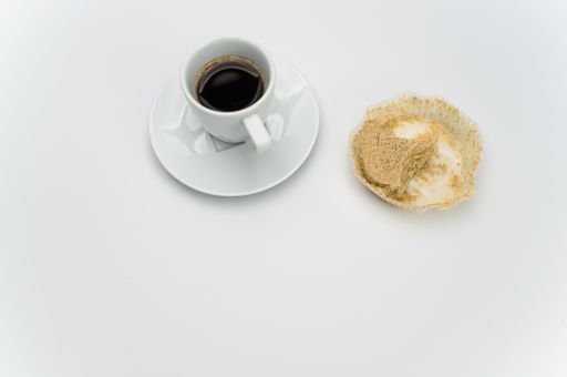 black hot ristretto coffe in a white stoneware cup with plate with nibbled pie on a white surface with text space
