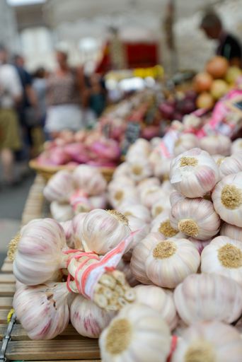 A vertical shot of ripe garlic bulbs on a stall in a French market with a blurry background