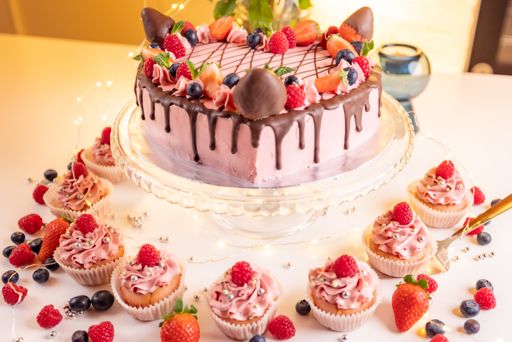 A closeup shot of a strawberry cake and some cupcakes on a table