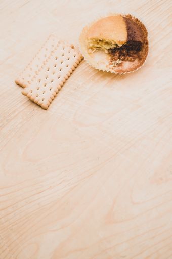 nibbled organic chocolate cupcake and biscuits on a rough wooden background with text space