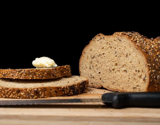 The freshly sliced loaf of delicious bread on a wooden board and black background