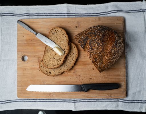 A top-view of freshly sliced loaf of delicious bread on a wooden board and black background