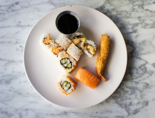 An overhead shot of sushi rolls with a teriyaki sauce on a round white plate
