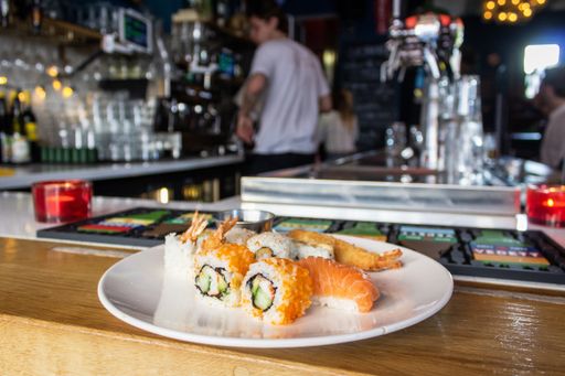A close shot of sushi rolls on a white plate on the counter with a blurred background