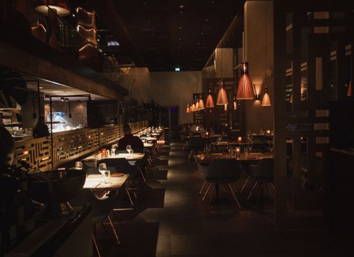 An interior shot of a dark cafe with light brown walls and lights hanging off the ceiling