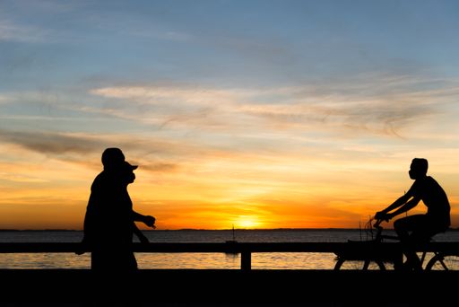 A Silhouette of people walking, running, cycling, talking and enjoying the sunset on Ribeira beach
