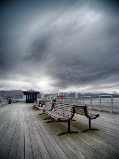 A vertical shot of benches on the pier on a cloudy day