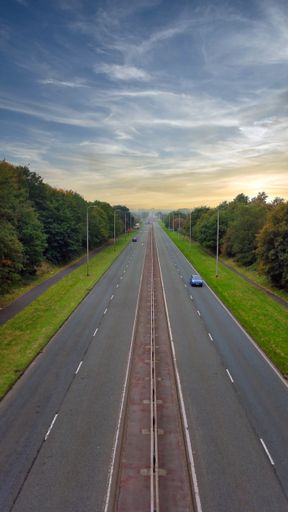 A vertical shot of a long highway on a cloudy morning