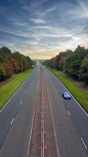 A vertical shot of a long highway on a cloudy morning