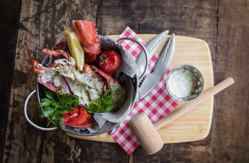 An overhead shot of boiled crab with eggs and vegetable leaves in a bucket on a wooden tray