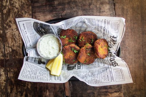 An overhead shot of fried falafels near a sauce on a tray with a wooden surface in the background