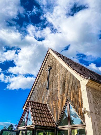 A low angle shot of the wooden facade of a German church against a cloudy sky