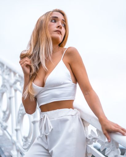 A vertical shot of a female wearing a white top and pants on the stairway in San Sebastian, Spain