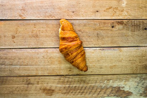 A top view shot of a tasty croissant on a wooden table