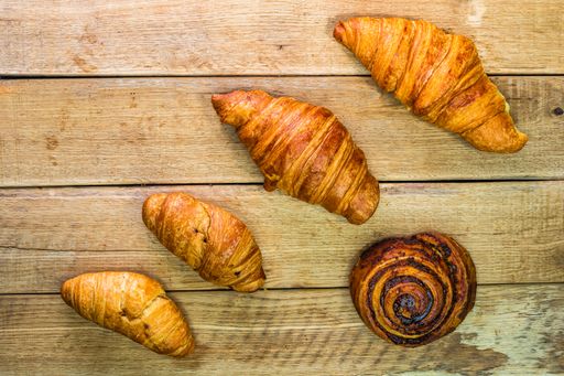 A top view of fresh croissants and cinnamon on a wooden table