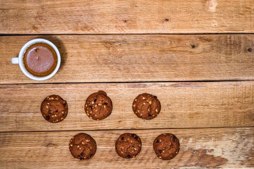 A cup of coffee and six fresh biscuits in the wooden background with a copy space