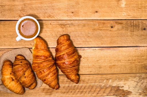 The fresh croissant and biscuits on wooden table. Coffee, food, and breakfast concept. Desserts, fresh pastries, and coffee. Top view and copy space