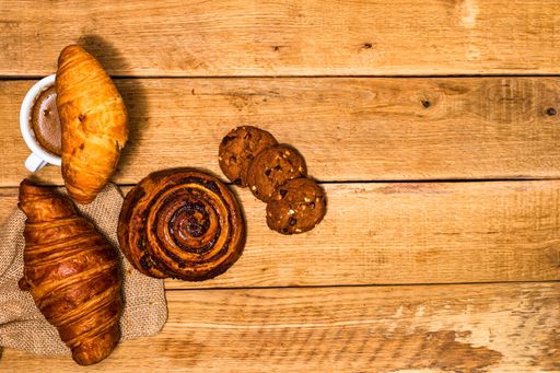 The fresh croissant and biscuits on wooden table. Coffee, food, and breakfast concept. Desserts, fresh pastries, and coffee. Top view and copy space
