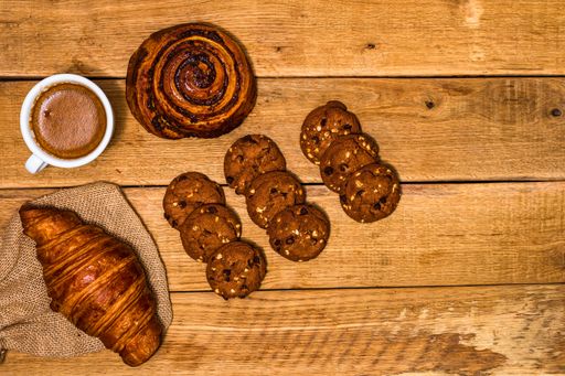 The fresh croissant and biscuits on wooden table. Coffee, food, and breakfast concept. Desserts, fresh pastries and coffee. Top view and copy space