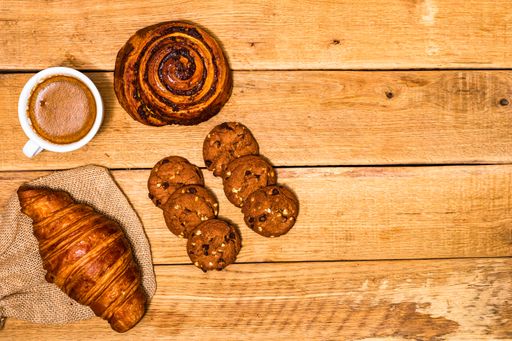 The fresh croissant and biscuits on wooden table. Coffee, food, and breakfast concept. Desserts, fresh pastries and coffee. Top view and copy space