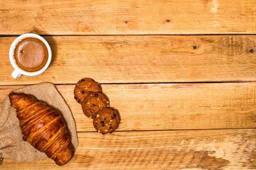 The fresh croissant and biscuits on wooden table. Coffee, food, and breakfast concept. Desserts, fresh pastries and coffee. Top view and copy space