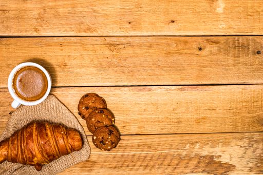 A fresh croissant and biscuits on a wooden table. Coffee, food, and breakfast concept. Desserts, fresh pastries and coffee. Top view and copy space