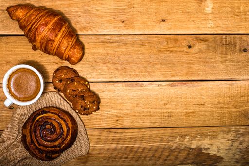 A top view shot of fresh pastries, biscuits, and coffee on a wooden table