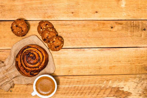 A closeup of the fresh puff pastry with a cup of coffee on the wooden table. Top view, copy space.