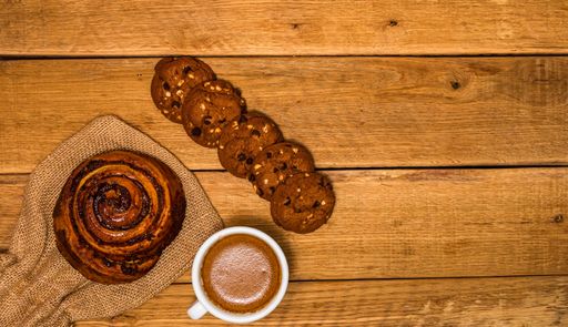 A top view shot of fresh pastries, biscuits, and coffee on a wooden table