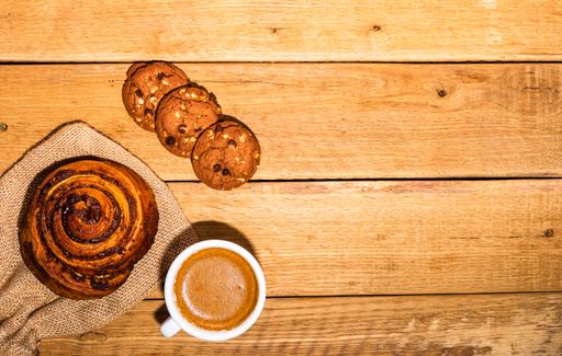 A top view of fresh pastries, biscuits, and a coffee cup in the wooden background with a copy space