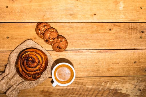 Fresh coffee and pastry on the wooden background with a copy space. Yummy breakfast and dessert