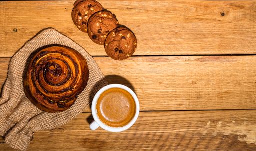 A top view of fresh coffee and yummy desserts on the wooden surface with copy space