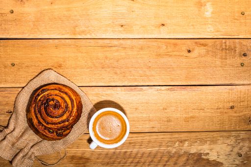 A top view of pastry and cup of coffee on wooden table with copy space
