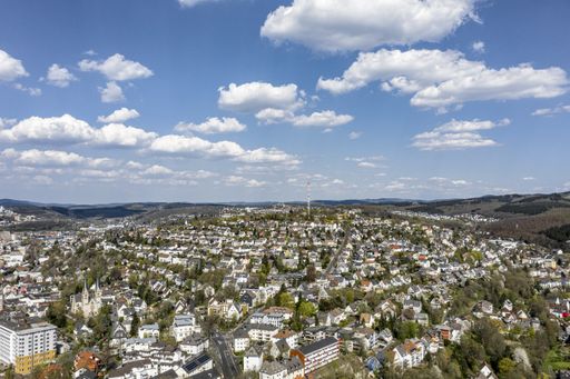 A high angle shot of a beautiful city surrounded by hills under the blue sky