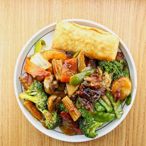 A high angle shot of a plate of delicious Chinese duck and vegetables on a wooden surface
