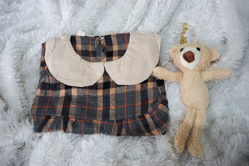 A top view of a cute dress for a little baby girl on a furry white soft background