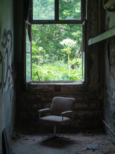 A vertical shot of an old chair in an abandoned room