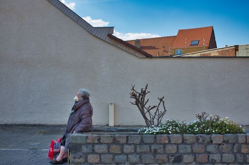 A shot of a female leaning against a salvaged block raised bed wearing a face mask at daytime