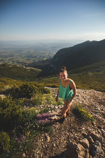 A serene landscape of a cheerful female hiker climbing up themountain