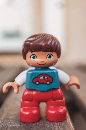 Lego Duplo plastic boy figurine in soft focus background.