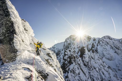 Winter extreme mountaineering and alpinism on alpine peaks. Sunset over a climber or alpinist climbing in alpine like mountain landscape.