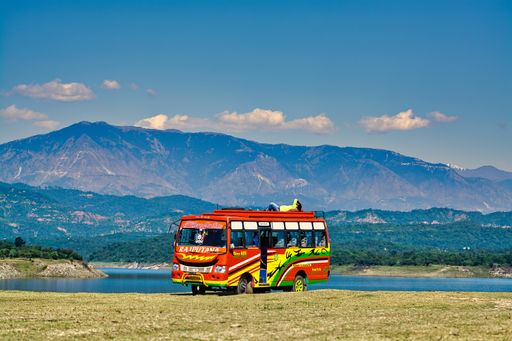 A beautiful view of the tourist bus in the field in the background of the lake and mountains