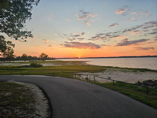 Scenic sunset over a tranquil beach with a winding path and vibrant sky, capturing nature's beauty.