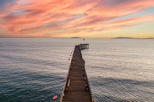 A mesmerizing view of the wooden pier over the wavy sea water at sunset in Ventura, California