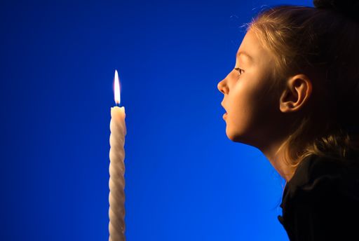 A cute Caucasian girl about to blow a single candle isolated