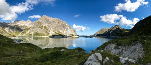 A scenic view of a calm lake and mountain landscape under a clear blue sky