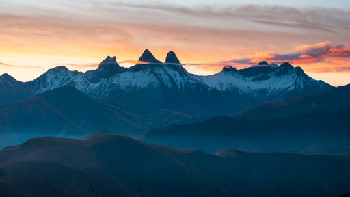 A scenic view of Aiguilles d'Arve mountain against a beautiful sunrise sky as seen from Col de la Croix de Fer in Savoie, France