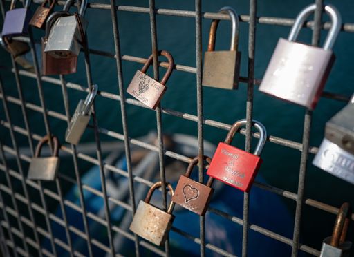 Love locks attached to a metal fence overlooking a body of water, symbolizing eternal love and commitment.